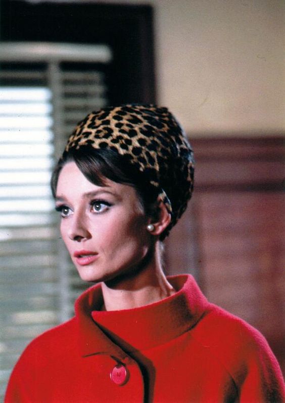 Audrey Hepburn's style in Charade, 1963. She wears a red wool coat with a cool leopard print hat.