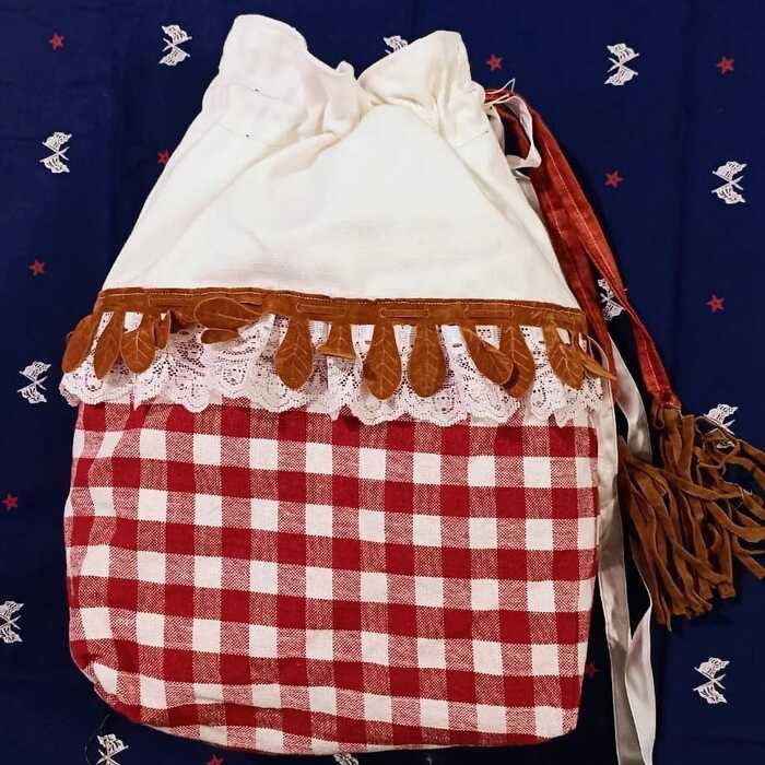 A pouch with checked bottom and a lining inside with a hanging string. It is a sling pouch.