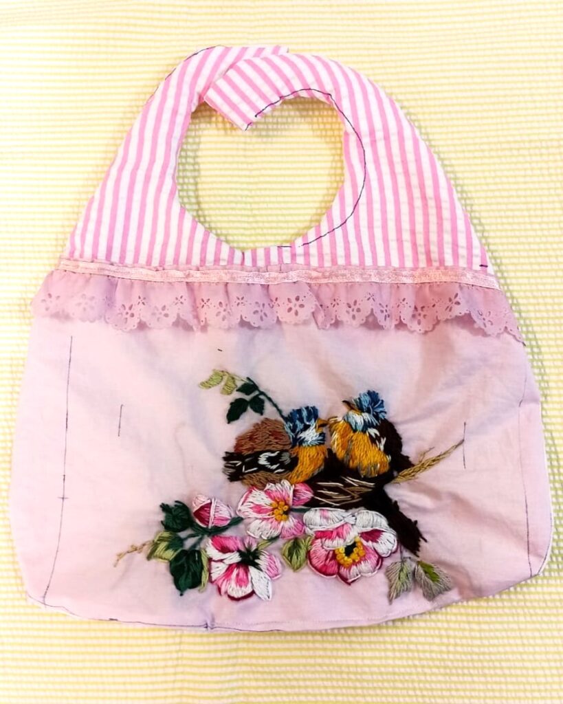 Pink pouch with sparrows and flower embroidery designs.